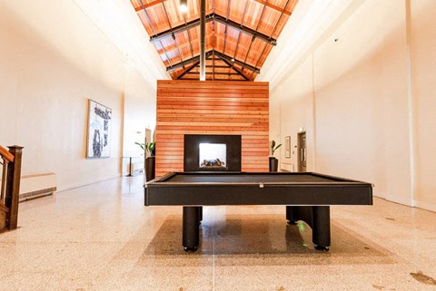 A room with a fireplace and a pool table at Addison on Fourth Apartments, Seattle, WA